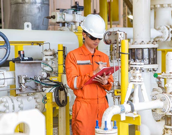 Production operator on offshore oil and gas central processing platform while checking and logging reading value of differential pressure gauge for process control system.